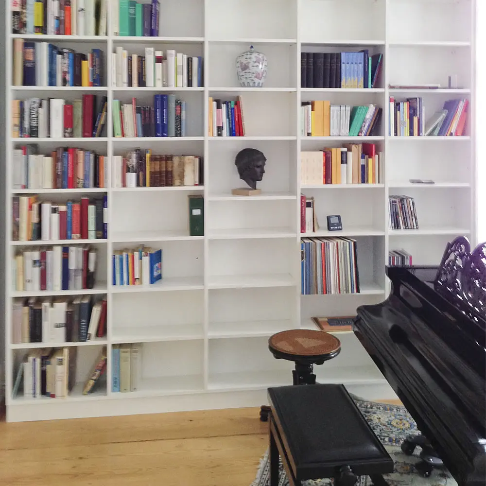 weiße Bücher-Regalwand, davor schwarzes Piano